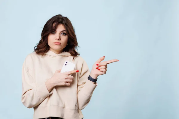 charming studio shot, a beautiful brunette teenager is captured in the midst of a joyful laugh as she points with her finger towards the copy space, exuding a sense of optimism and positivity.