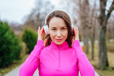 beautiful and athletic young woman enjoys some much needed time alone in the great outdoors, surrounded by nature and free from the stresses of everyday life. With her smartphone and headphones