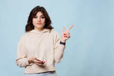 This teenage girls smiling face and pointing gesture towards the copy space in the background creates a playful and happy atmosphere in this studio shot, perfectly capturing the carefree spirit of