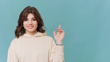 The playful expression on this teenage girls face as she points towards the copy space in the background perfectly captures the light-hearted spirit of adolescence. Her laughter and cheerful demeanor