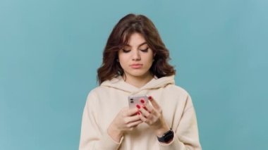 Esmer saçlı genç bir kızın kafası karışıktır ve akıllı telefonu tutarken omuzlarını silker. Bir sorunu ya da muammayı anlamakta zorlanıyor gibi görünüyor..