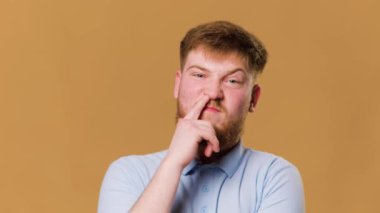 A comic image of a teenager with a crazy expression and finger in nose in a studio shot. bizarre photo of a guy with an unusual habit of putting his finger in nose, captured in a studio shot.