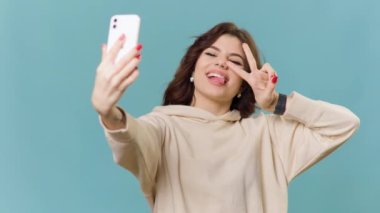 Genç kız blogcu eğleniyor, dışarıda selfie kaydediyor, akıllı telefona bakıyor, jestler göstererek eğleniyor, video aramasından zevk alıyor. Günlük kaydı, yaşam tarzı