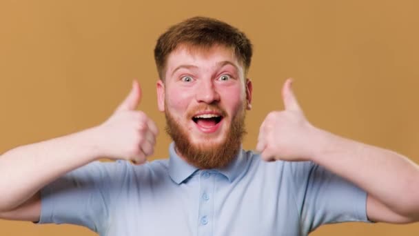 若い赤毛の男はスタジオで撮影された笑顔で親指をあきらめます スタジオの肖像画で喜びの表情と親指を持つ思春期の男性 — ストック動画