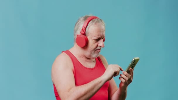 Senior Citizen Gadget Hand Listening Music Headphones Studio Blue Background — ストック動画