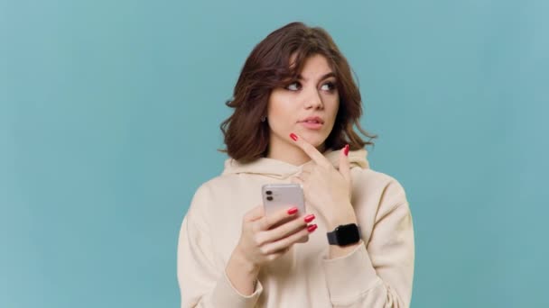 Przemyślana Piękna Biała Dziewczyna Myśli Czymś Smartfonem Podejmuje Decyzje Zastanawia — Wideo stockowe