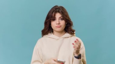 Genç bir kızın akıllı telefonunu tutarken kafası karışır. Hoş ve güzel yüzü kafa karışıklığı ve soru işaretleri gösterir..