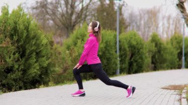 An athletic woman training outdoors, enjoying a healthy lifestyle and staying active with her headphones on