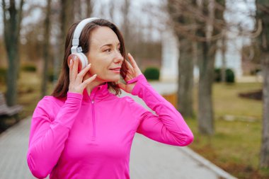 Koşudan sonra dinlenen olgun bir kadının portresi. Parkta koşan güzel bir son sınıf öğrencisi. Koşu yaparken müzik dinleyen kadın koşucu.