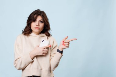 charming studio shot, a beautiful brunette teenager is captured in the midst of a joyful laugh as she points with her finger towards the copy space, exuding a sense of optimism and positivity.