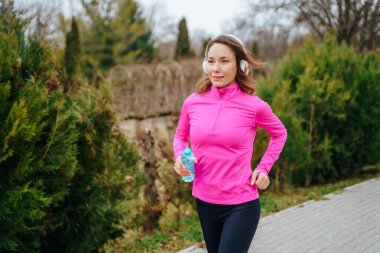 Güneşli bir günde koşan İspanyol bir koşucu bir an için şişesinden su içmek için duraklıyor. Amerikalı bir bayan koşucu sabah koşusu sırasında ferahlatıcı bir su molası veriyor..