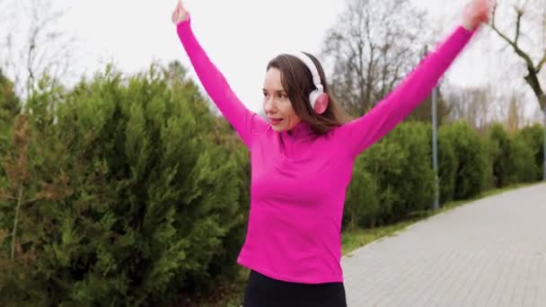一名穿着时髦运动服 头戴耳机 早上在外面锻炼的女运动员 — 图库视频影像
