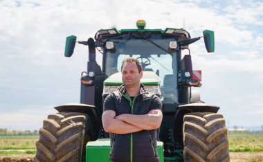 Bu resim verimli toprak hazırlama ve sürme için gerekli olan güçlü traktör gücünü gösteriyor. Çiftlikte çalışan adamlar memnuniyetlerini göstermek için başparmaklarını kaldırıyorlar..