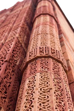 Kutub Minar freskleri ve motifleri kule duvarına yakın çekim. Kutub Minar anıtlarındaki antik kırmızı kumtaşı arka planı. Ya da Hindistan, Delhi 'deki Kutub Minar anıtındaki Duvar Detayları.