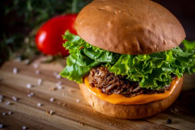 Çedarlı domuz sandviçi, marul ve ahşap arka planda mor soğan.