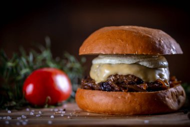 Ahşap arka planda peynirli sığır burger ve sos.