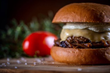 Ahşap arka planda peynirli sığır burger ve sos.