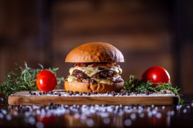 Hamburger, peynir, domuz pastırması ve ahşap arka planda sos.