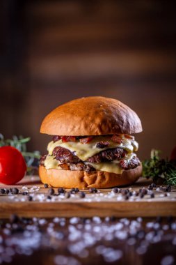 Hamburger, peynir, domuz pastırması ve ahşap arka planda sos.