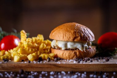Peynirli sığır burger ve ahşap arka planda patates kızartması.