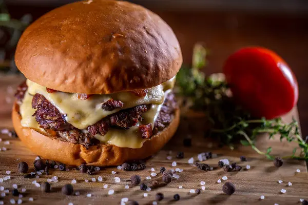 Craft beef smash burger with cheese, bacon and sauce on wooden background