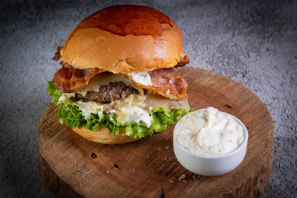 Two smash burgers with cheese, bacon, letuce and garlic sauce. Rustic craft burger.