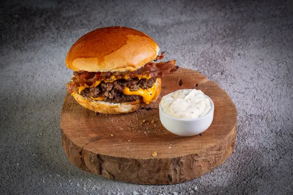 Two smash burgers with cheddar cheese, bacon and garlic sauce. Rustic craft burger.