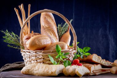 Koyu arkaplandaki ahşap masada sepetteki ekmek çeşitleri. Fırın Çeşitliliği.