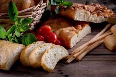 Koyu arkaplandaki ahşap masada sepetteki ekmek çeşitleri. Fırın Çeşitliliği.