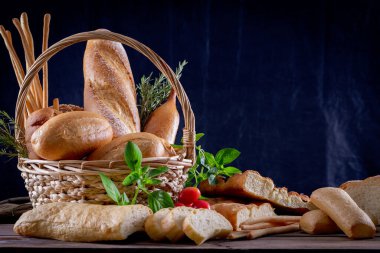 Koyu arkaplandaki ahşap masada sepetteki ekmek çeşitleri. Fırın Çeşitliliği.