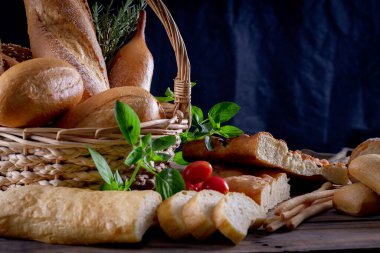 Koyu arkaplandaki ahşap masada sepetteki ekmek çeşitleri. Fırın Çeşitliliği.