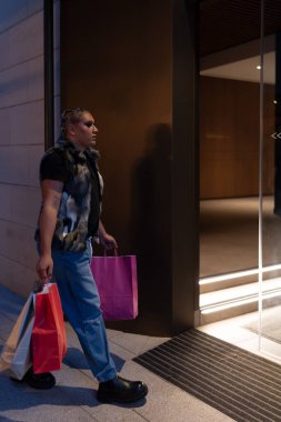 İkili olmayan kişi kış alışverişi için bir mağazaya giriyor, elinde torbalar var. Mağazalarda çeşitlilik, cinsiyet kimliği ve alışveriş sezonu kavramı.