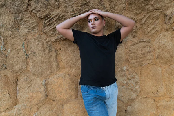 Portrait of a Latin American non-binary person, looking away while posing leaning against a wall. Concept of gender and ethnic diversity. With copy space.