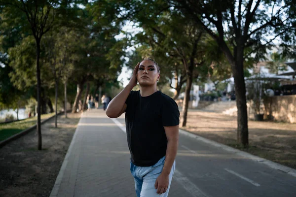 Portrait of a young non-binary person of Latin American origin looking at the camera while posing standing in the street. Concept of ethnic and gender diversity. With copy space.