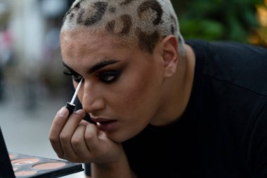 İkili cinsiyet ayrımı yapmayan, sokakta makyaj yapan bir genç. Genç Güney Amerikalı profesyonel makyöz dışarıda kendine dokunuyor. Cinsiyet kimliği, makyaj ve yaşam tarzı kavramları.