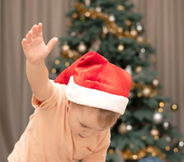 stock image A little boy in a santa claus hat is dancing on the background of a christmas tree. without a face. Close-up. soft focus. Christmas concept. 2023