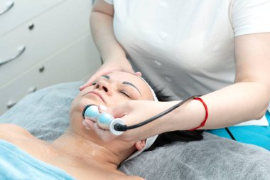 Sağlığa. Kozmetoloji. Yaşlanmış bir kadın güzellik salonundaki bir kanepede uzanıyor. Yüz gerdirme ameliyatı ve radyo dalgası aparatıyla kaldırma işlemi için. Yakın plan. Kavram.