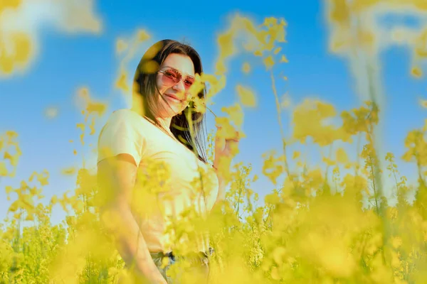 Uma Menina Bonita Óculos Sol Fica Campo Flores Amarelas Contra — Fotografia de Stock