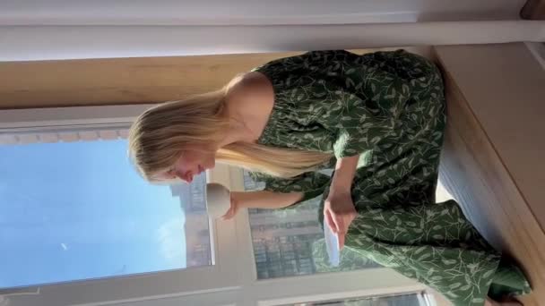 Piękna Szczęśliwa Dziewczyna Domowej Roboty Zielone Ubrania Siedzi Przy Oknie — Wideo stockowe