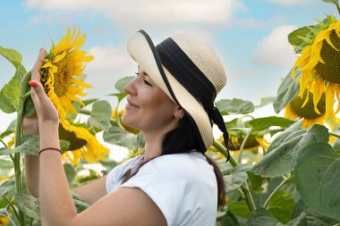 Hasır şapkalı güzel ve mutlu bir kız mavi gökyüzüne karşı sarı ayçiçekleri olan bir tarlada duruyor. Barış kavramı. Ukrayna 'nın sembolü. Yakın plan..