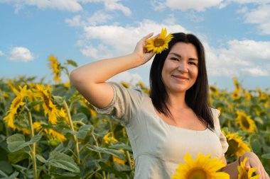 Ukrayna konsepti. Barış sembolü. Beyaz gömlekli, uzun saçlı, güzel ve mutlu bir beyaz kız mavi gökyüzüne karşı sarı ayçiçeği tarlasında duruyor..