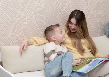 Aile kavramı. 19 yaşında güzel bir kız ve 5 yaşındaki bir oğlan çocuk odasında yatağında oturmuş birlikte kitap okuyorlar. Ortak bir öğrenme ve beraberlik anını gösteriyor. Yatay