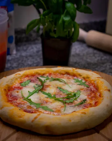 stock image A homemade pizza topped with melted mozzarella and fresh arugula, capturing the perfect blend of flavors in a mouthwatering and vibrant dish.