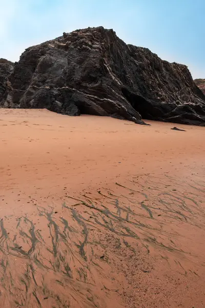 stock image A tranquil beach, a rocky outcrop, and the soft sand, capturing the serene beauty of coastal nature.