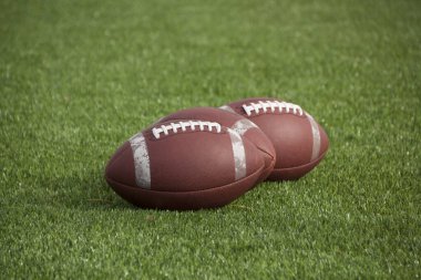 Amerikan futbolcuları çimlerin üzerinde dinleniyor, harekete geçmeye hazır, maç başlamadan önce oyunun heyecanını ve heyecanını yakalıyorlar..