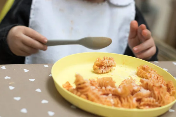 2歳の赤ちゃんがトマトソースでパスタを食べる — ストック写真