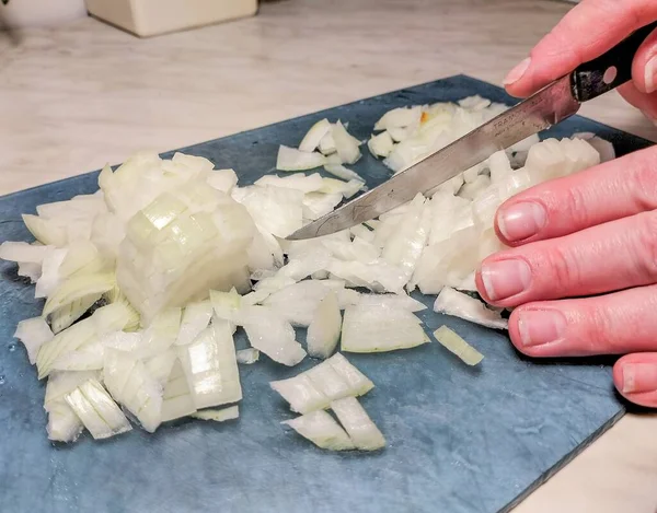 Female hands cutting bulb onion. Cooking. Close up