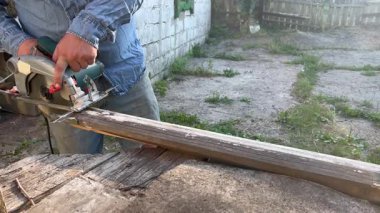 Marangoz arka bahçede dairesel testere kullanarak tahta kesiyor.