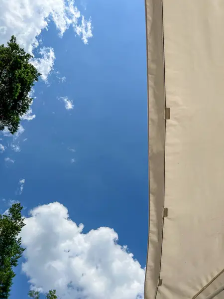 Mavi gökyüzü ve beyaz bulutların olduğu açık bir günde bej rengi güneş kremi doğrudan güneş ışığına karşı koruma sağlar.