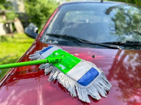 Kırmızı bir arabayı yıkamak için profesyonel temizlik malzemesi ve ekipman kullanan araba temizleme